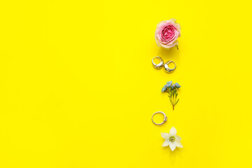 Stylish earrings with ring and different beautiful flowers on yellow background