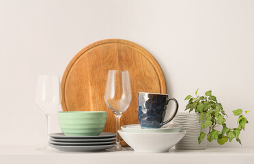 Clean dishware and houseplant on table against white background. Closeup