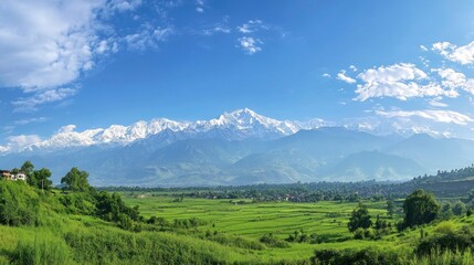 A panoramic view of majestic mountains and lush green fields under a blue sky.