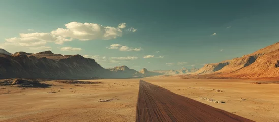 Fototapete Rund Vast expansive desert landscape with a long straight asphalt road leading towards distant mountains under a clear blue sky. © Cyber Shutter