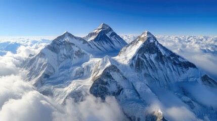 Obraz premium aerial view of majestic snow-capped mountains under clear blue sky with clouds creating a stunning natural landscape background