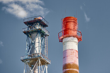 Chemical plant distillation column towers under blue sky with scattered clouds during daylight hours