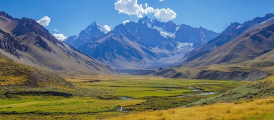 Majestic mountain landscape with lush green valley under a vibrant blue sky and dramatic cloud formations in nature