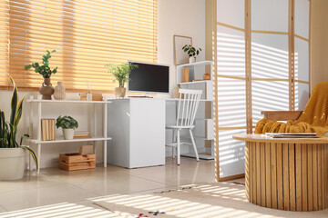 Workplace with computer and folding screen in interior of living room