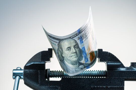 Concept of financial stress or recession.  Dollar being squeezed in a vice.