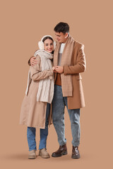 Loving young happy couple in winter clothes hugging on beige background