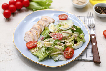 Plate of tasty chicken Caesar salad with tomatoes and bowl of peppercorn on white background