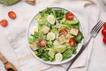 Plate with tasty Caesar salad on white background