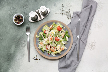 Plate with tasty chicken Caesar salad on grunge background