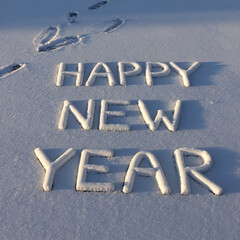 A happy new year written in the snow with footprints in the snow
