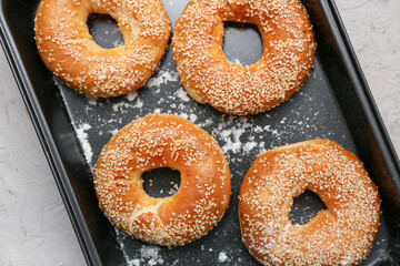 Baking dish of tasty bagels with sesame seeds on grey background