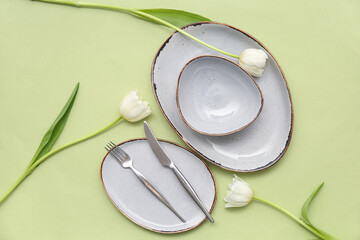 Stylish table setting with beautiful tulip flowers on green background