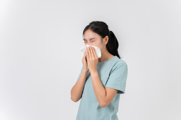 A sick Asian woman sneezing and blowing her nose, suffering from a runny nose, flu, or allergy.