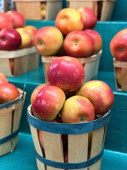 Small wooden baskets with green stripes, piled high full of fresh red apples for sale in a farm market.