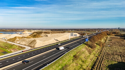 Industrial landscape with highway and cars traffic aerial drone view from above, modern motorway road in industrial zone, Netherlands