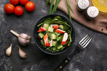 Bowl of salad with crab sticks, spinach, cucumber and ingredients on black grunge background © Pixel-Shot