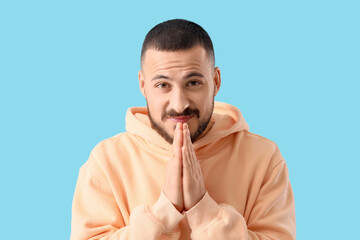 Apologetic young man on blue background, closeup