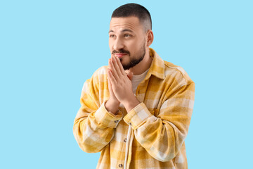 Apologetic young man on blue background