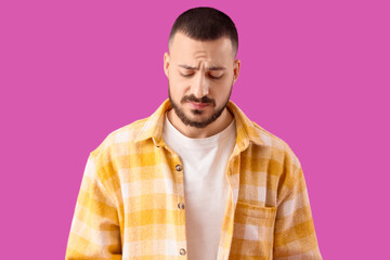 Apologetic young man on violet background