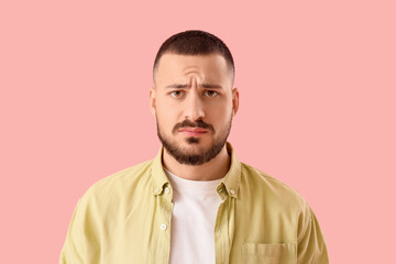 Apologetic young man on pink background, closeup