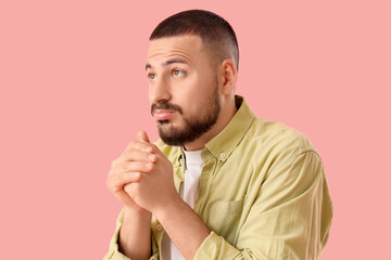 Apologetic young man on pink background, closeup