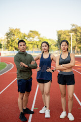 Confident Asian athlete runners in sportswear, standing with their arms crossed in a stadium.