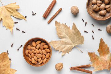 Composition with almond nuts, spices, acorns and fallen leaves on grey background
