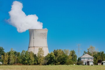 Large cooling tower of a nuclear power plant, emitting steam on a clear day, with rural landscape in the foreground. DAVIS–BESSE NUCLEAR POWER STATION, OAK HARBOR, OHIO, UNITED STATES