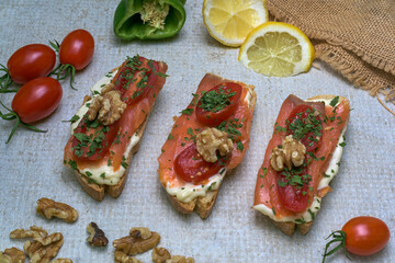 Salmon canapé with tomato, cheese, walnuts on rustic background