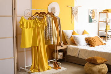 Rack with different clothes in modern bedroom