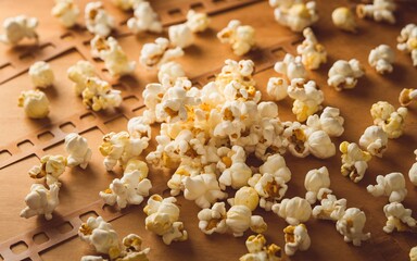 playful popcorn explosion, Scattered popcorn on a wooden surface.