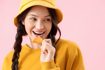 Young girl eating tasty nachos on pink background