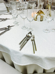 A beautifully arranged white table cloth which is elegantly set with silverware and sparkling wine glasses placed gracefully on top of it, creating an inviting dining atmosphere