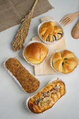 five toasted bread topped with shredded beef, cheese sausage, chocolate, pandan, on a white table photographed with studio lighting and wooden theme props