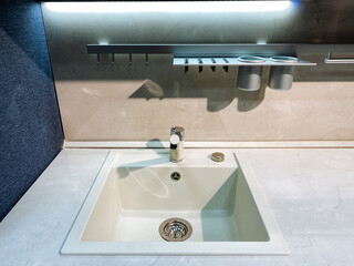 A beautifully designed kitchen sink, complete with an efficient drain and a stylish faucet, is situated atop a lovely counter, adding functionality and elegance to your cooking space