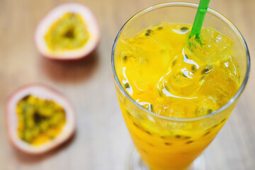 close up of iced passion fruit juice in a glass with passion fruit half slice on table