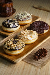 several donuts with chocolate topping, tiramisu, peanut cheese and sprinkles, on a wooden base, photographed with studio light with a wooden theme