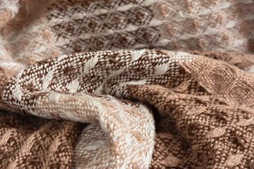 Brown plaid texture. Presentation of the fashionable color of 2025 mocha mousse. Warm, cozy shades of chocolate, beige, brown. The texture of a woolen plaid in close-up. The concept of home comfort