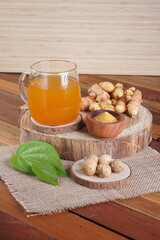 herbal drink made from turmeric, betel leaves and oak galls photographed in a studio setting with traditional Indonesian theme props