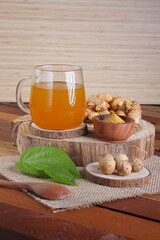 herbal drink made from turmeric, betel leaves and oak galls photographed in a studio setting with traditional Indonesian theme props
