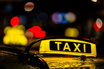 Neon taxi sign against the blurred background of the city center lights.