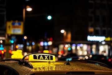 Neon taxi sign against the blurred background of the city center lights.