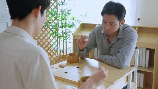Asian young men playing board game Go during competition in community. 