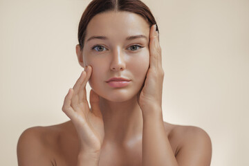 Close-up of a young woman gently touching her face, showcasing glowing, healthy skin. Perfect for beauty, skincare, or facelift surgery concepts. High-quality image for cosmetic or medical advertising