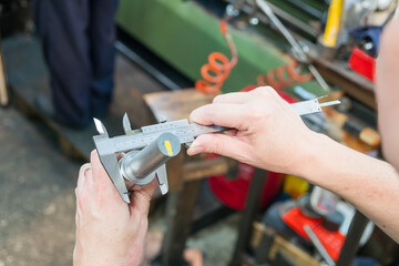Close up scene the machine operator measuring dimension of turning parts by Vernier caliper.