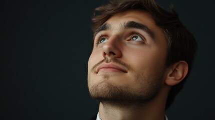 Obraz premium Young Businessman Looking Thoughtfully Upwards with Visionary Focus