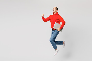 Full body young IT middle eastern man he wears red hoody casual clothes jump high hold closed...