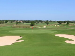 Fototapeta premium Scenic View of a Beautiful Golf Course Featuring Lush Greens, Sand Bunkers, and a Clear Blue Sky Perfect for Leisure Activities and Outdoor Recreation