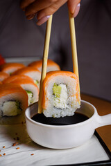 Philadelphia rolls are dipped in sauce with chopsticks