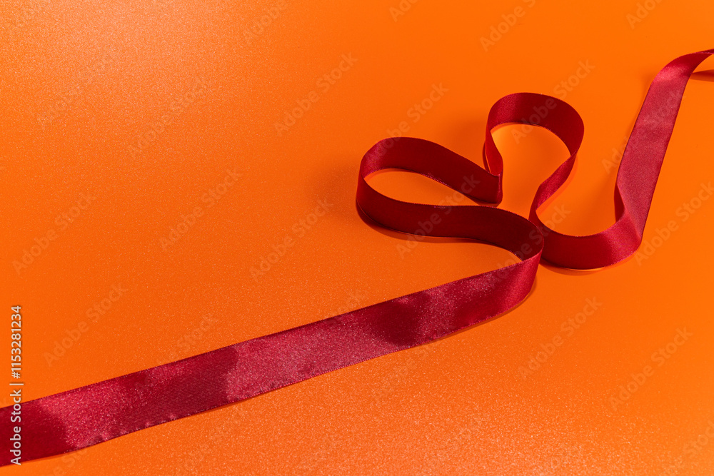 Poster red ribbon with a heart shape on a colored background